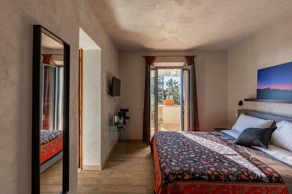 a bedroom with a bed and a door to a balcony at Casa Mustiola in Montalcino