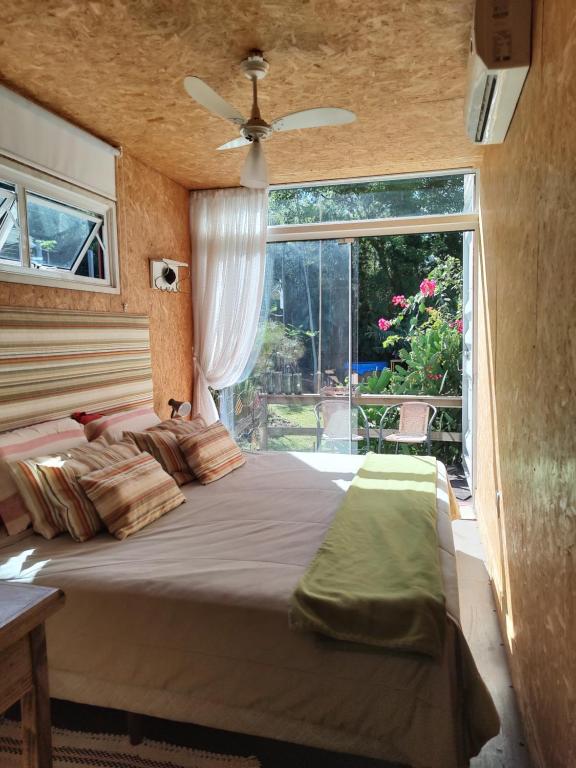 ein Schlafzimmer mit einem großen Bett und einem großen Fenster in der Unterkunft Casa Container in Santo Antônio
