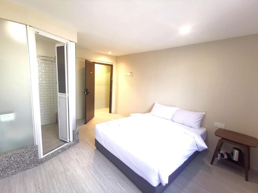 Maco Inn Century @Johor Bahru في جوهور باهرو: غرفة نوم بسرير ابيض ومرآة