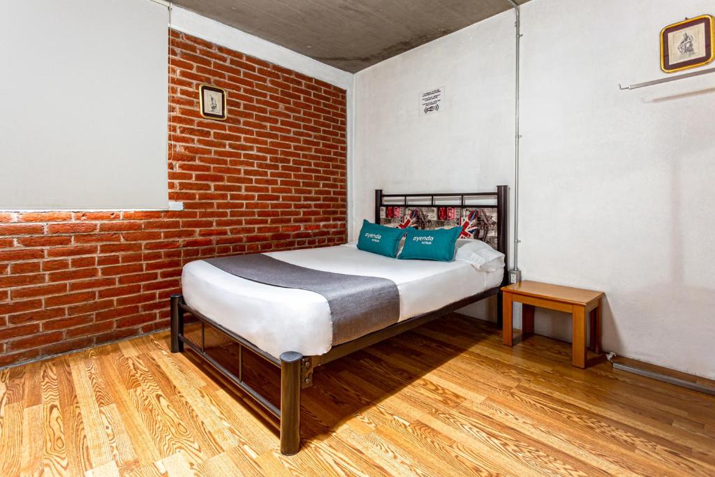 a bed in a room with a brick wall at Ayenda Casa Miranda Airport in Mexico City