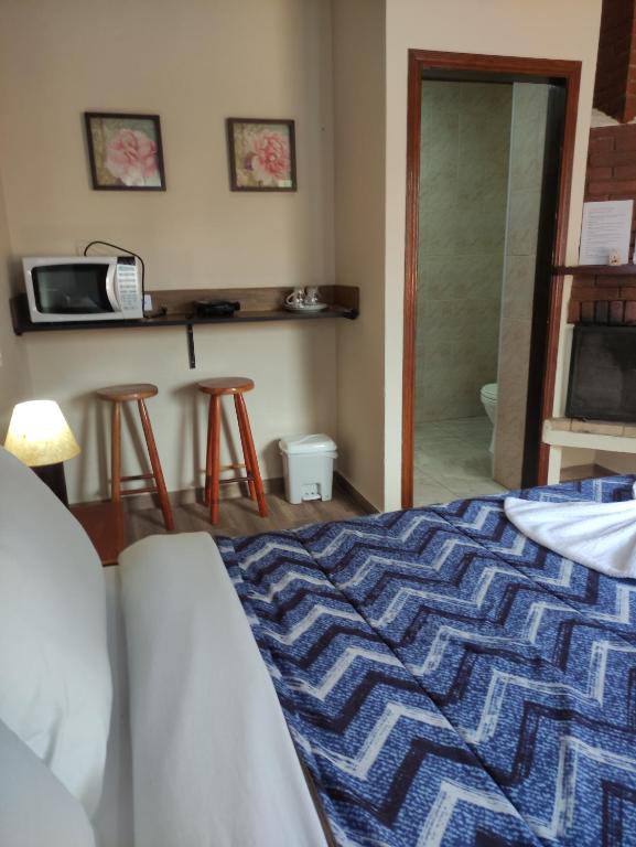 sypialnia z łóżkiem i kuchenką mikrofalową w obiekcie CHALES CARVALHOS w mieście Monte Verde