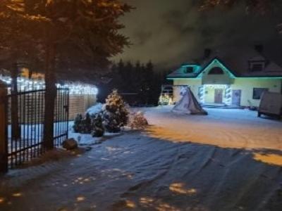 a house with a christmas tree in the snow at night at Noclegi u Dorki in Kurzętnik