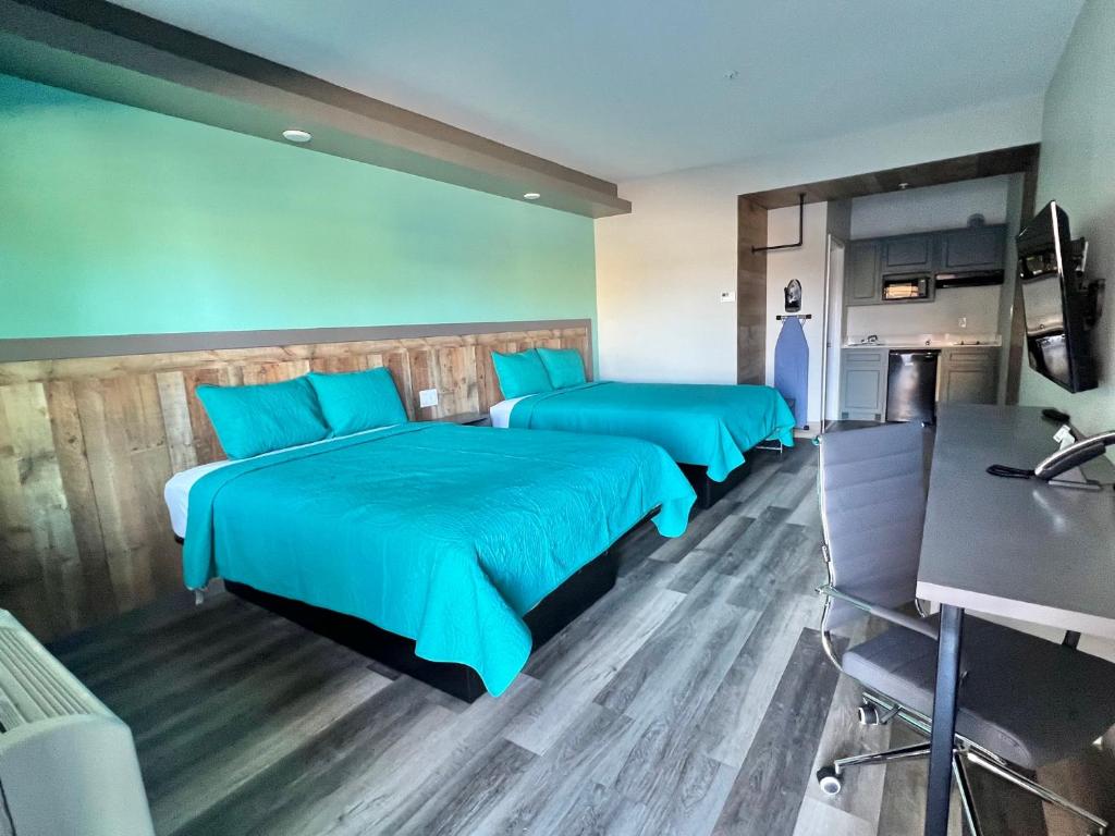 two beds in a room with blue sheets at The Residency Suites in Sugar Land
