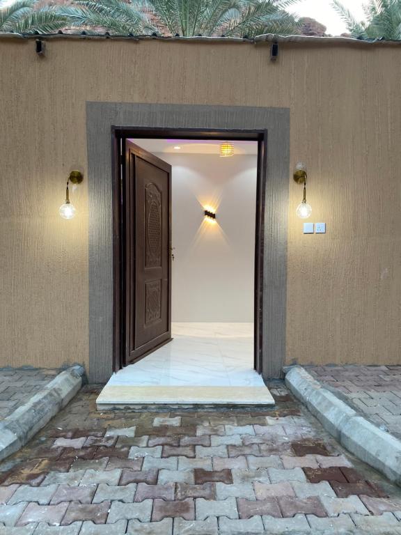 a door leading into a room with a brick floor and lights at شاليه الجبل الاحمر 3 in Al-ʿUla