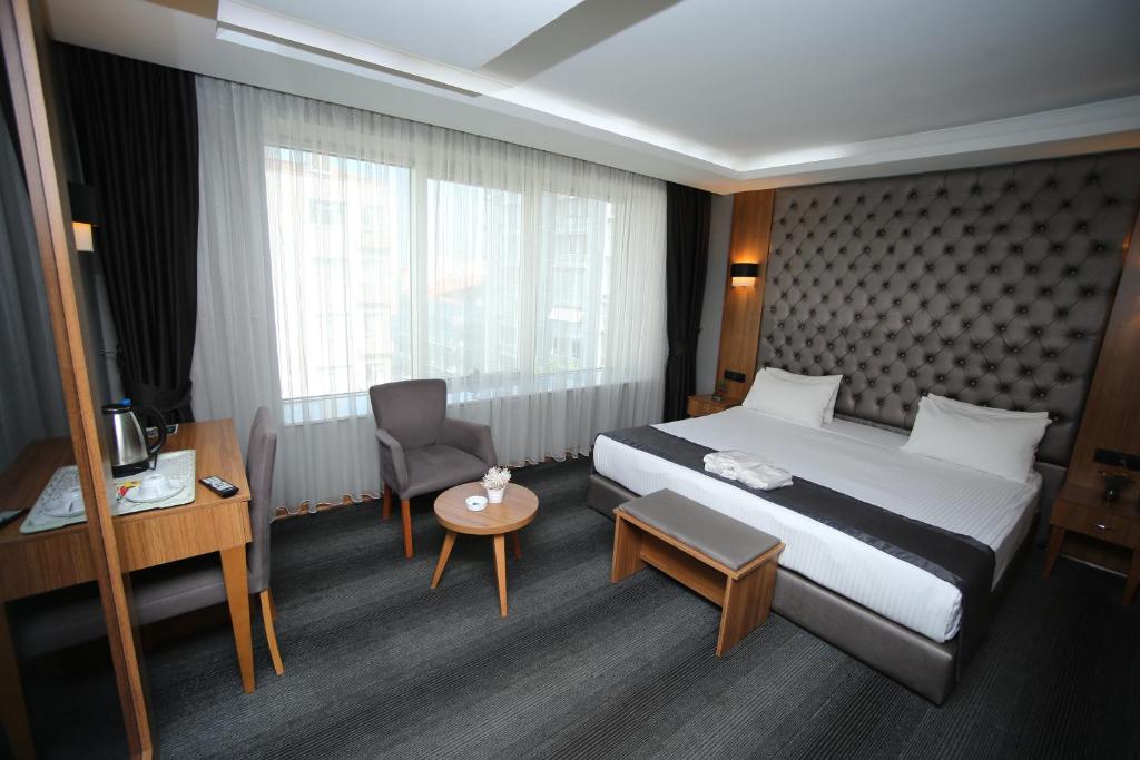 アンカラにあるGrand Silay Hotelの大きなベッドとデスクが備わるホテルルームです。