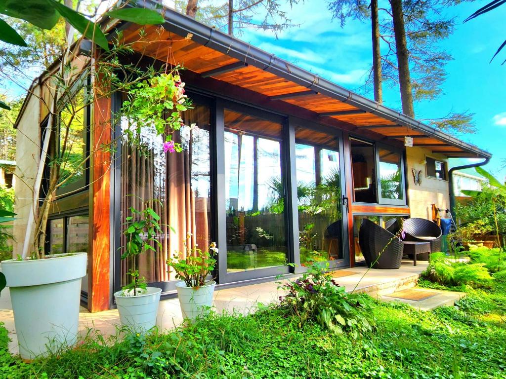 une maison avec de grandes fenêtres et des plantes dans la cour dans l'établissement House & Yard Sesil XS 60m to beach, à Ureki