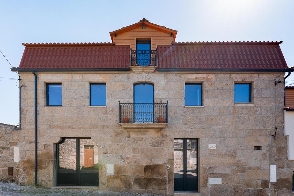 a large brick building with a balcony on top at Sevenfarm in Mangualde