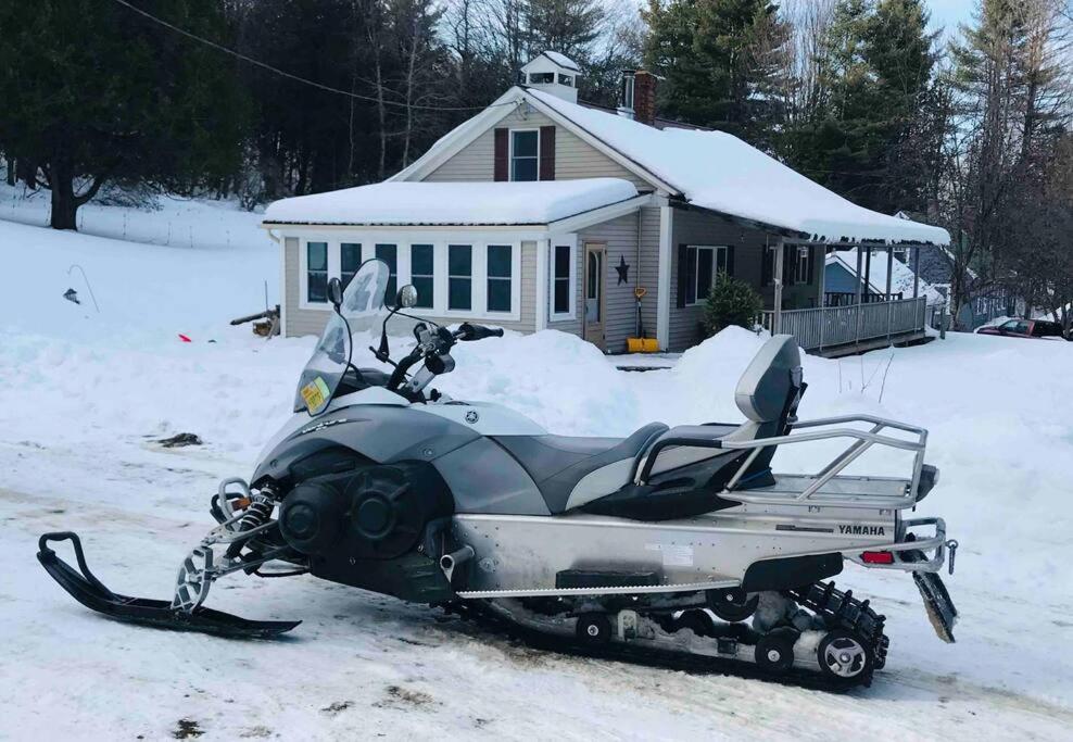 Una moto de nieve estacionada en la nieve frente a una casa en Hiking, MTB, four wheeling, fishing lakes, beaches, skiing, snowboarding,, en Barton