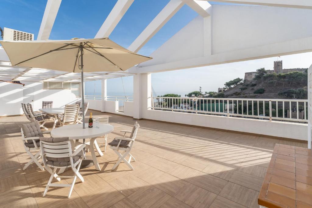 フエンヒロラにあるPenthouse Castilloのテーブルと椅子と傘のあるバルコニー