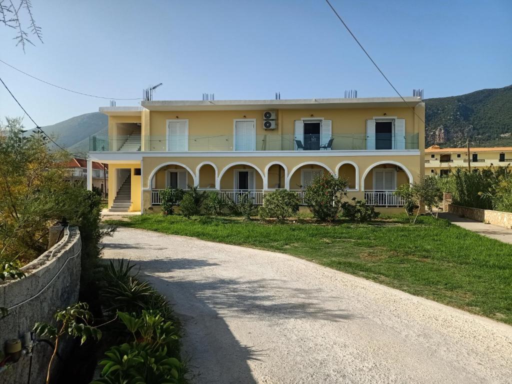 a large yellow house with a road in front of it at ALMIRIKI Studios & Apartments in Alykes