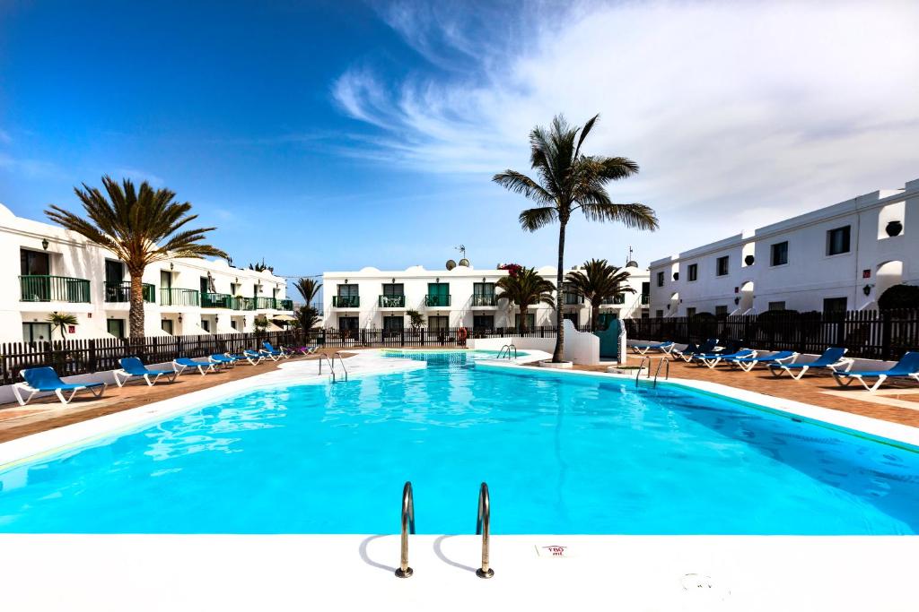 uma grande piscina com cadeiras e palmeiras em Sunshine San Valentin em Corralejo