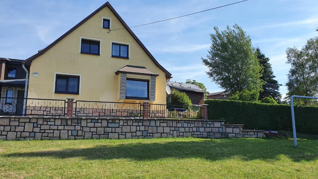 a yellow house with a brick retaining wall at Ferienhaus Bringfriede in Muldenhammer