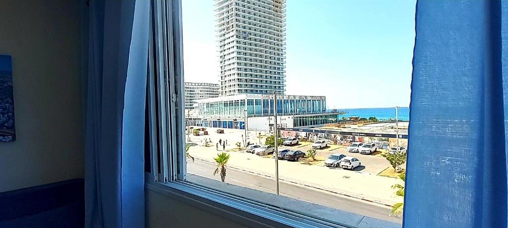 a window with a view of a parking lot and a city at Beachfront Studio Apartment Bat Yam 412 in Bat Yam