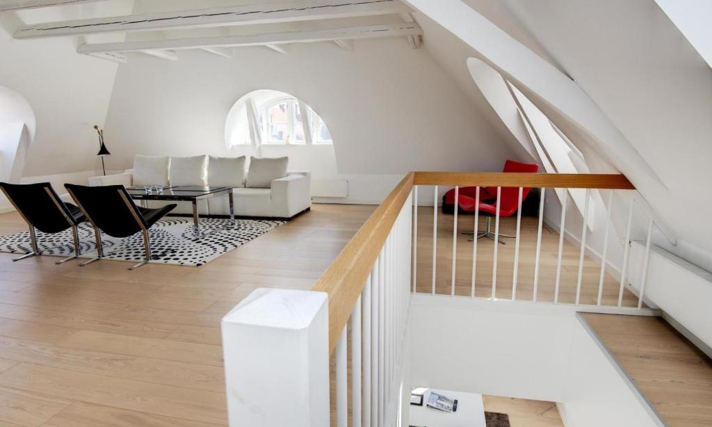 a living room with a table and chairs and a staircase at Penthouse Apartment Skagen in Skagen