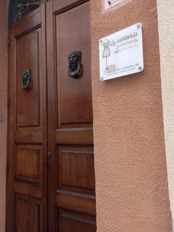 una puerta de madera con una señal en el lateral de un edificio en La sartoria, en Centuripe