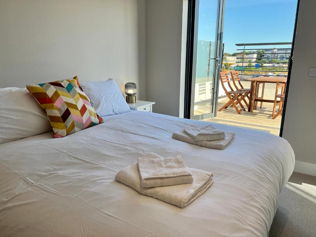 a white bed with towels on it with a balcony at SoHot Stays Sea View Apartments in Kent