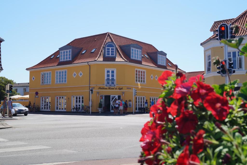 a yellow building with red flowers in front of it at Foldens Hotel in Skagen