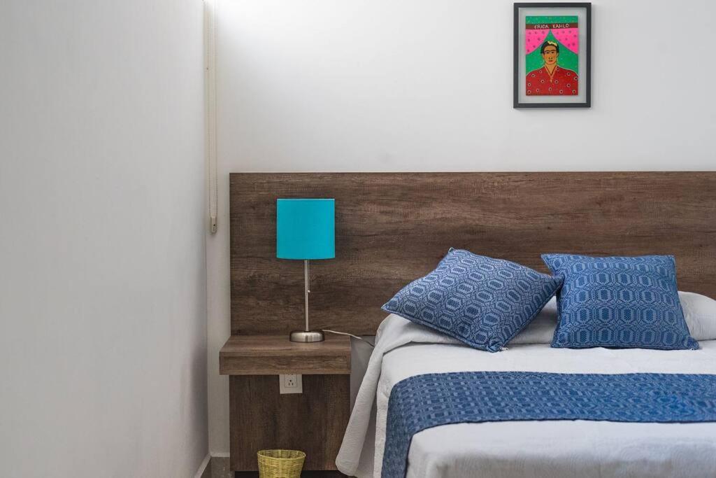 a bedroom with a bed with blue pillows and a blue lamp at JUUB More Oaxaca Impossible (R1) in Oaxaca City