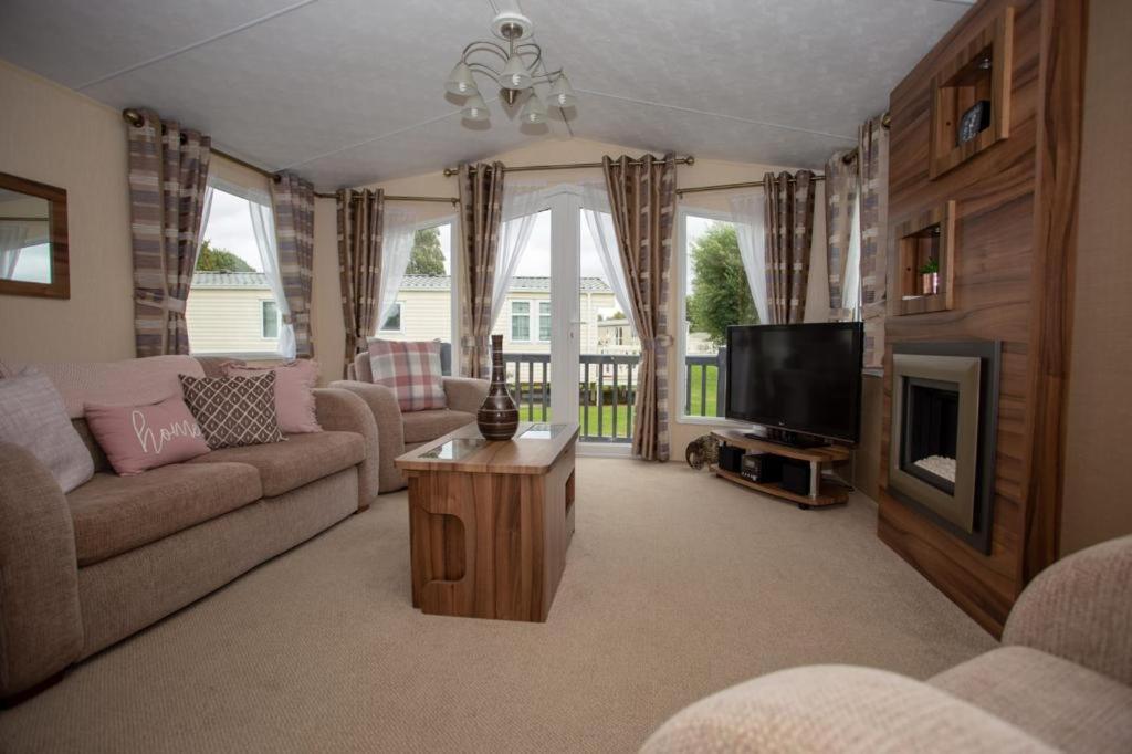 a living room with a couch and a tv at Willow View - Hoburne Cotswolds Holiday Park in South Cerney