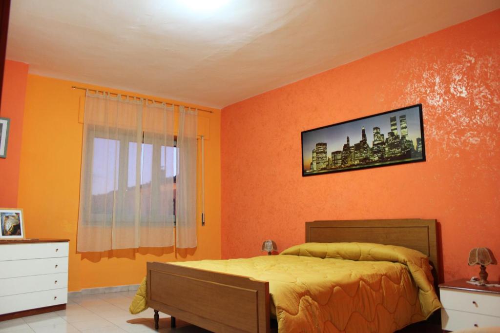 1 dormitorio con paredes de color naranja, 1 cama y ventana en La Vedetta Alpina, en Torricella Peligna