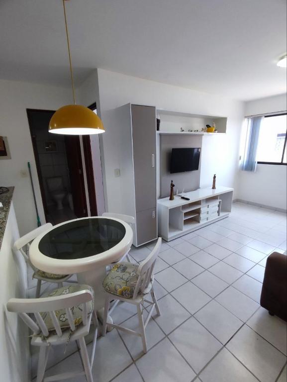 a living room with a table and chairs and a television at Apartamento com piscina a uma quadra da praia de jatiuca in Maceió