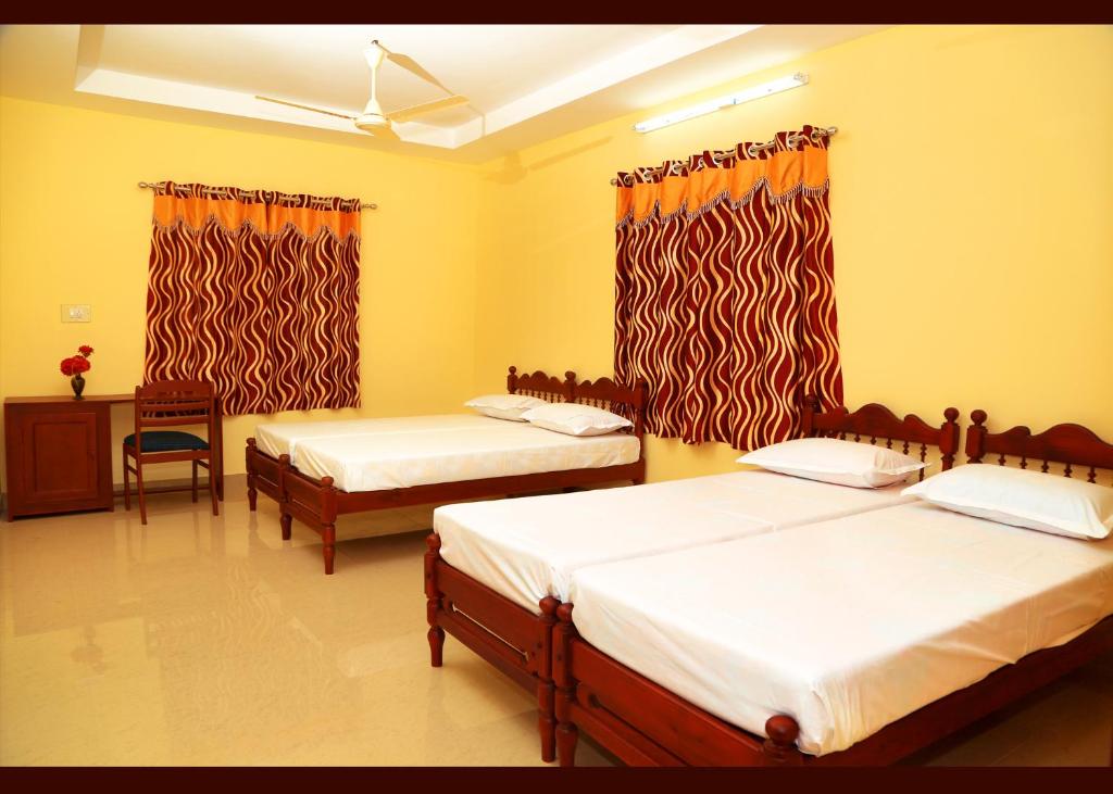 two beds in a room with yellow walls at Alapatt Homestay in Alleppey