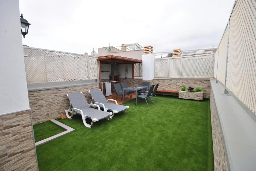 a patio with chairs and a table and grass at PLAYA DEL NORTE VIVIENDA VACACIONAL in Gáldar