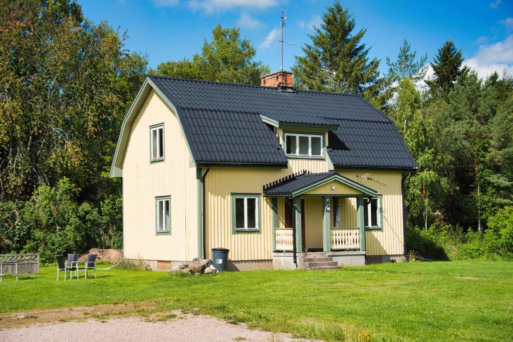 a small yellow house with a black roof at Gula huset, Lakene Ostgård in Lakene