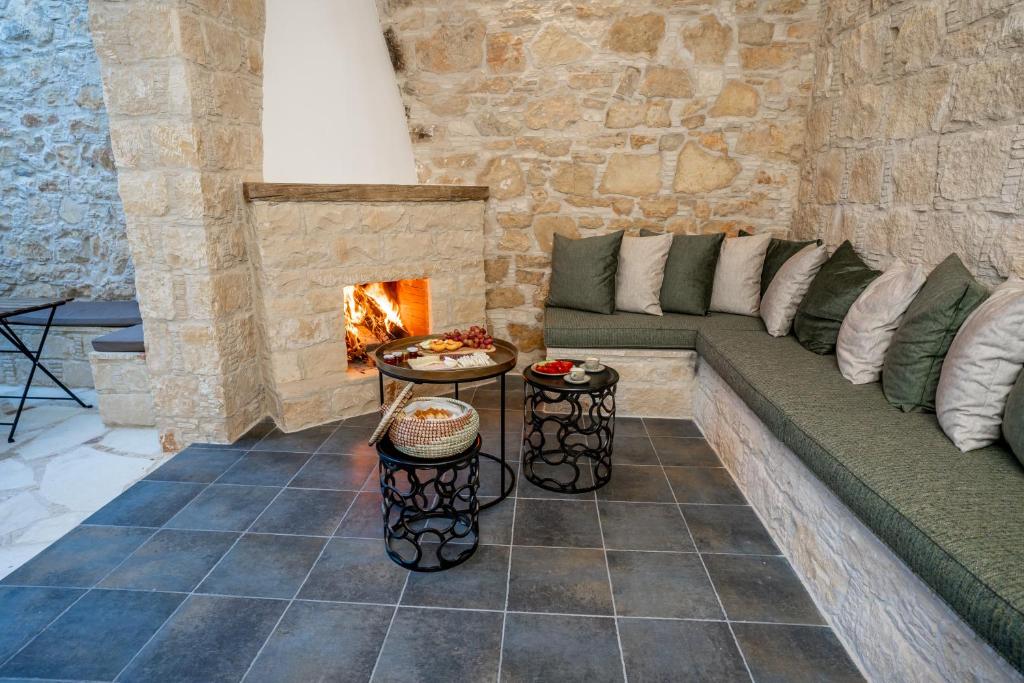 sala de estar con pared de piedra y chimenea en Palazzino Luxury Suites, en Lofou