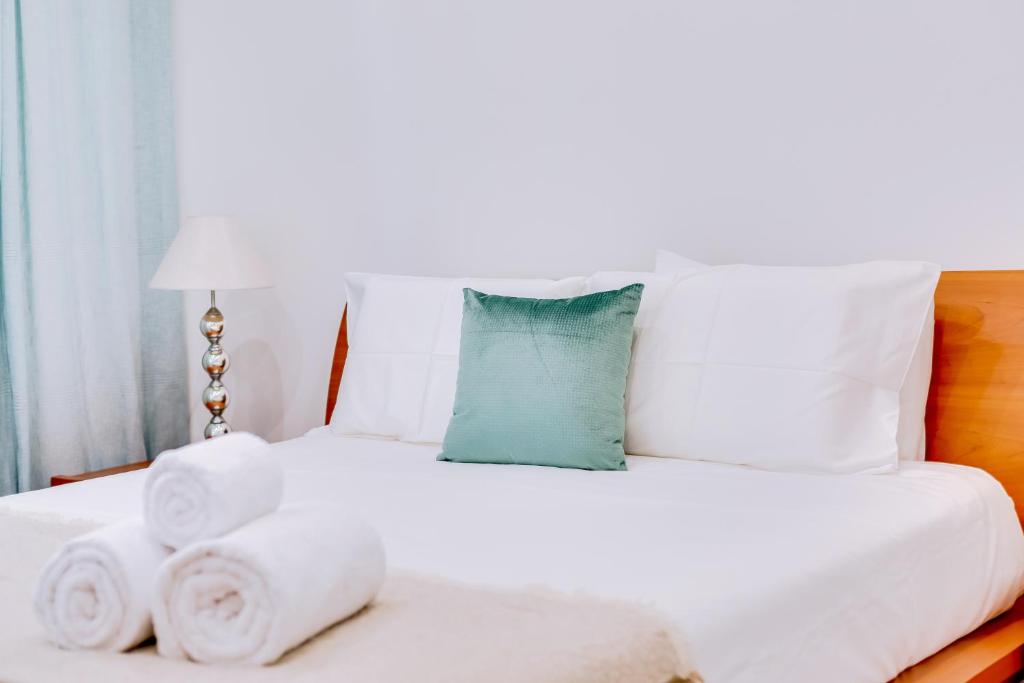 a white bed with towels and a blue pillow at Marina Star Guesthouse in Faro