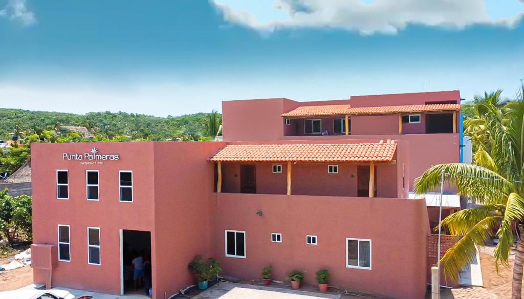 Hotel Punta Palmeras في غير متوفر: منزل وردي أمامه نخلة