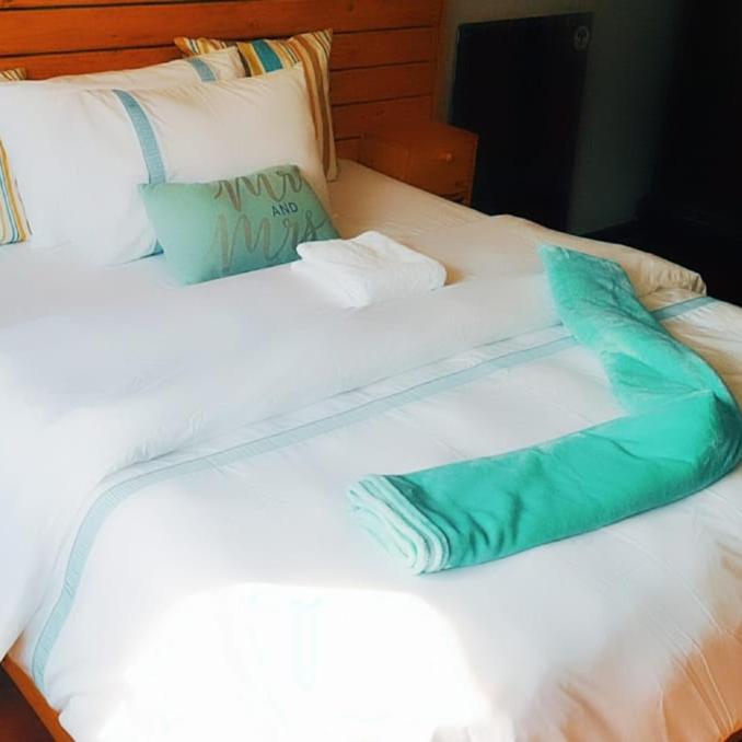 a white bed with a green pillow on it at Bedfort Accommodation in Cape Town