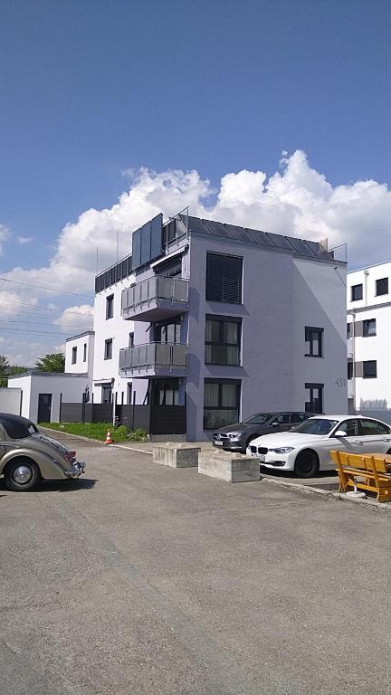 un edificio blanco con coches estacionados en un estacionamiento en Fewo S&S Buss, en Friedrichshafen