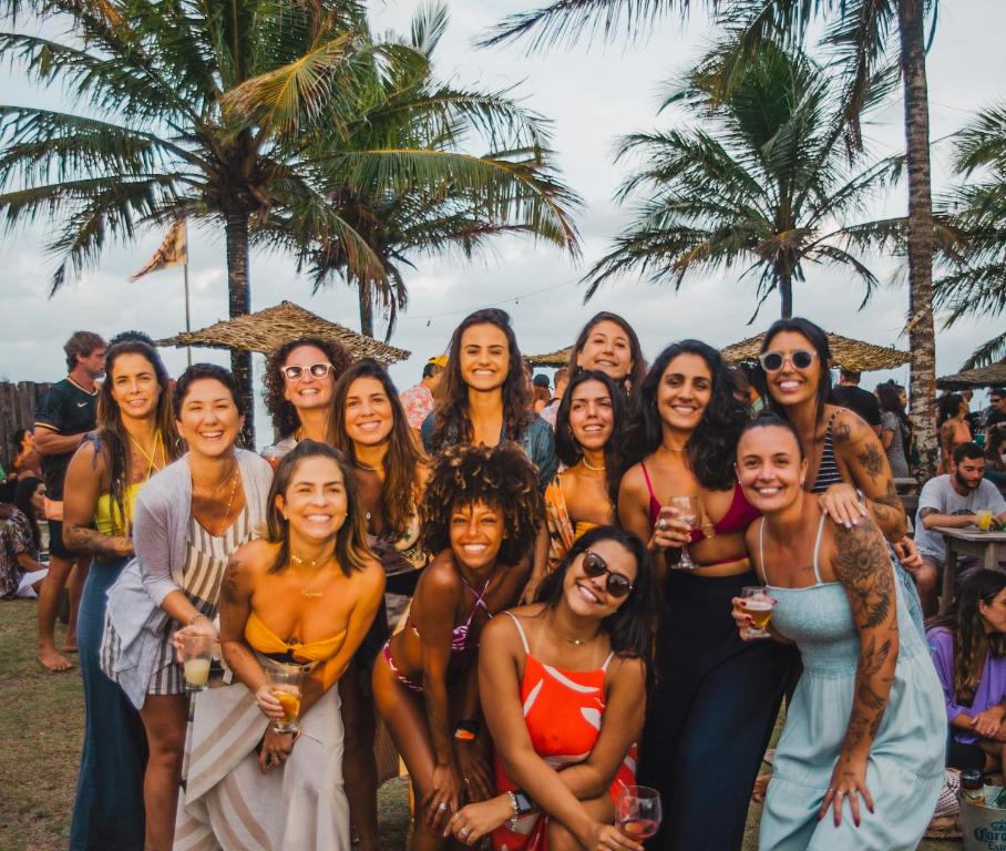 um grupo de mulheres posando para uma foto em uma praia em Caramuru Hostel Caraíva em Caraíva