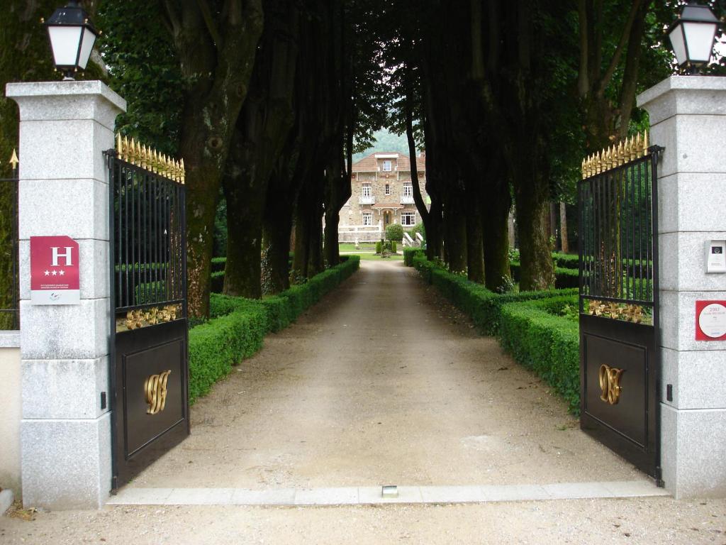 un cancello che conduce a una casa con alberi di Demeure de Flore a Lacabarède