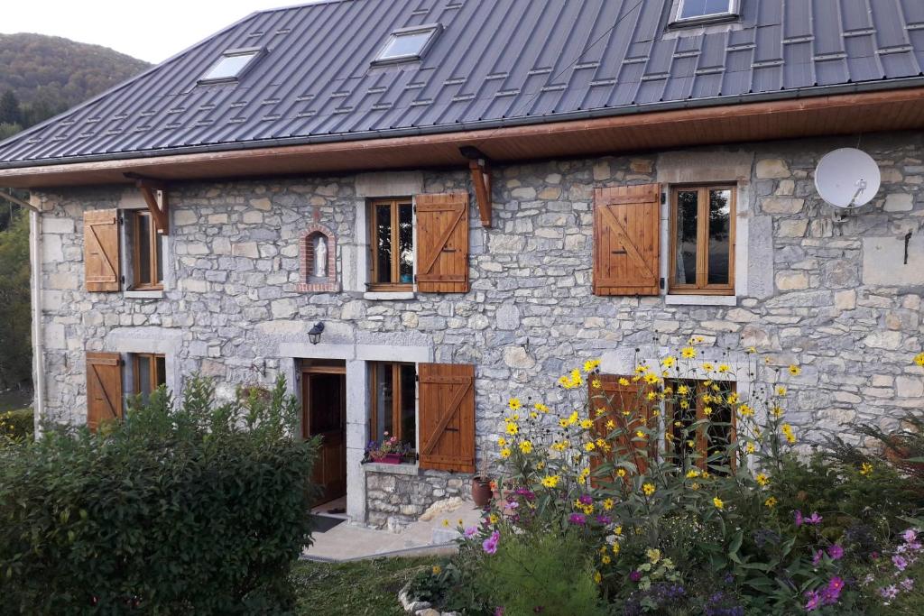 uma casa de pedra com um telhado preto e algumas flores em Gîte des Bruns en chartreuse em Entremont-le-Vieux