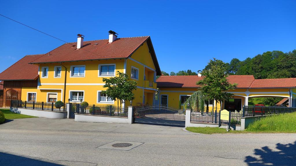 una casa amarilla con techo rojo en una calle en Ferienwohnungen Hanetseder, en Wallern an der Trattnach