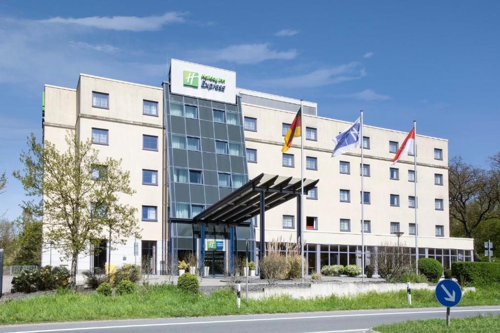 un immeuble de bureaux avec drapeaux devant lui dans l'établissement Holiday Inn Express Frankfurt Airport, an IHG Hotel, à Mörfelden-Walldorf