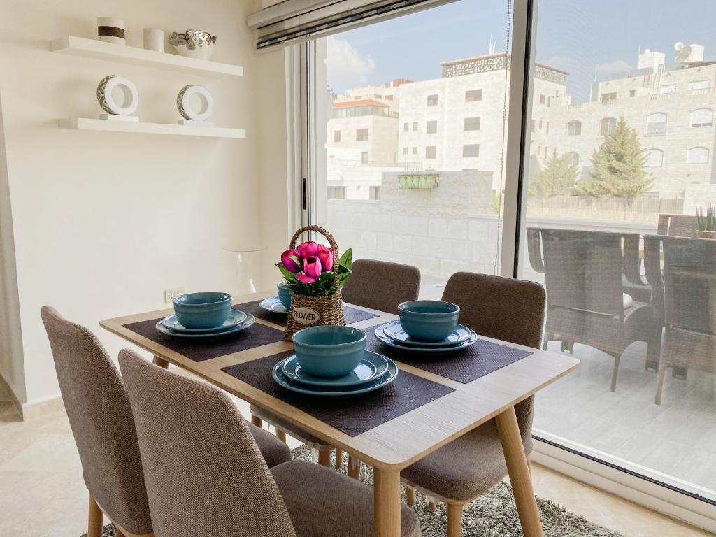 a dining room with a table and chairs and a window at 360 Rooftop Apartment in Dabouq in Amman