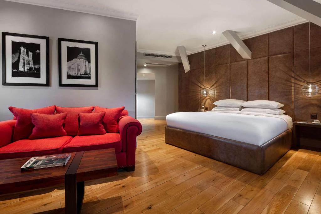 a bedroom with a bed and a red couch at Radisson Blu Hotel, London Bloomsbury in London