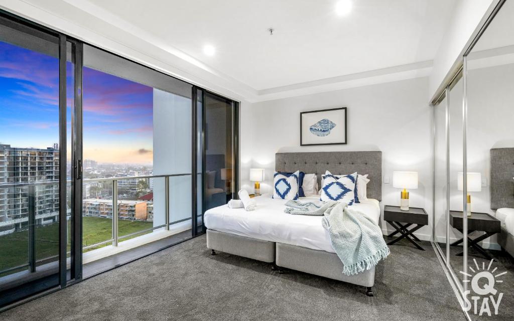 a bedroom with a bed and large glass windows at Avalon Apartments - QStay in Gold Coast