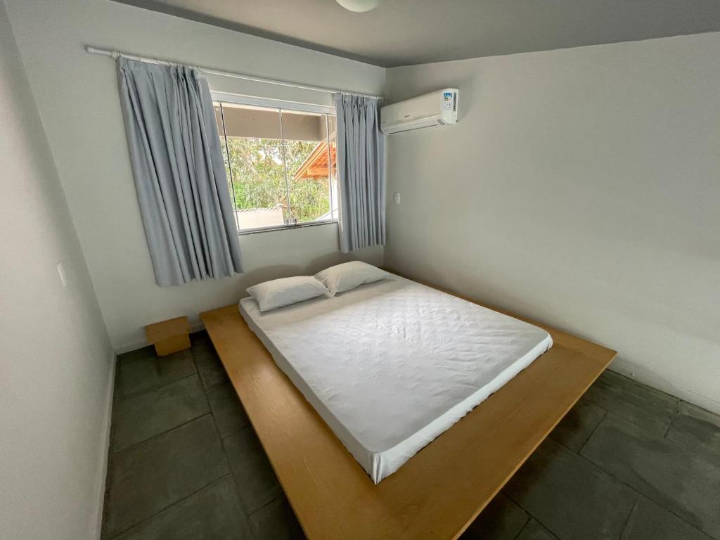 a small bedroom with a bed and a window at Casa pé na areia para até 14 pessoas em bombinhas in Bombinhas