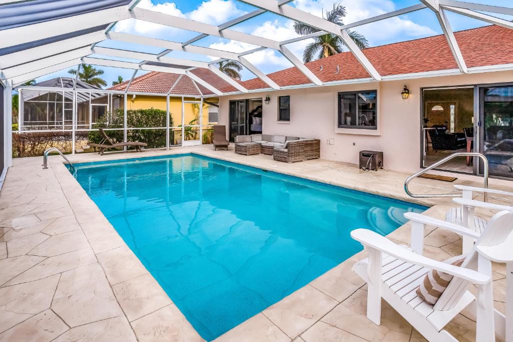 a swimming pool with a pergola and a house at Menorca Court in Marco Island