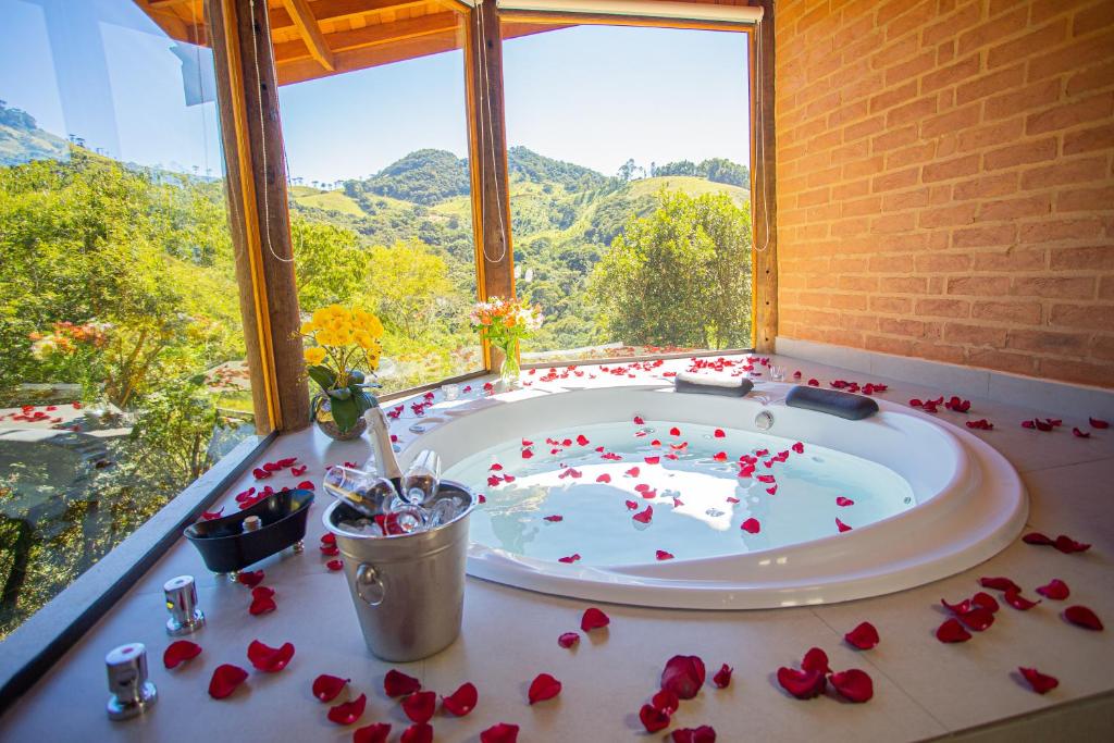 - une baignoire dans une chambre avec des roses au sol dans l'établissement Chalés Alto dos Pires, à São Bento do Sapucaí