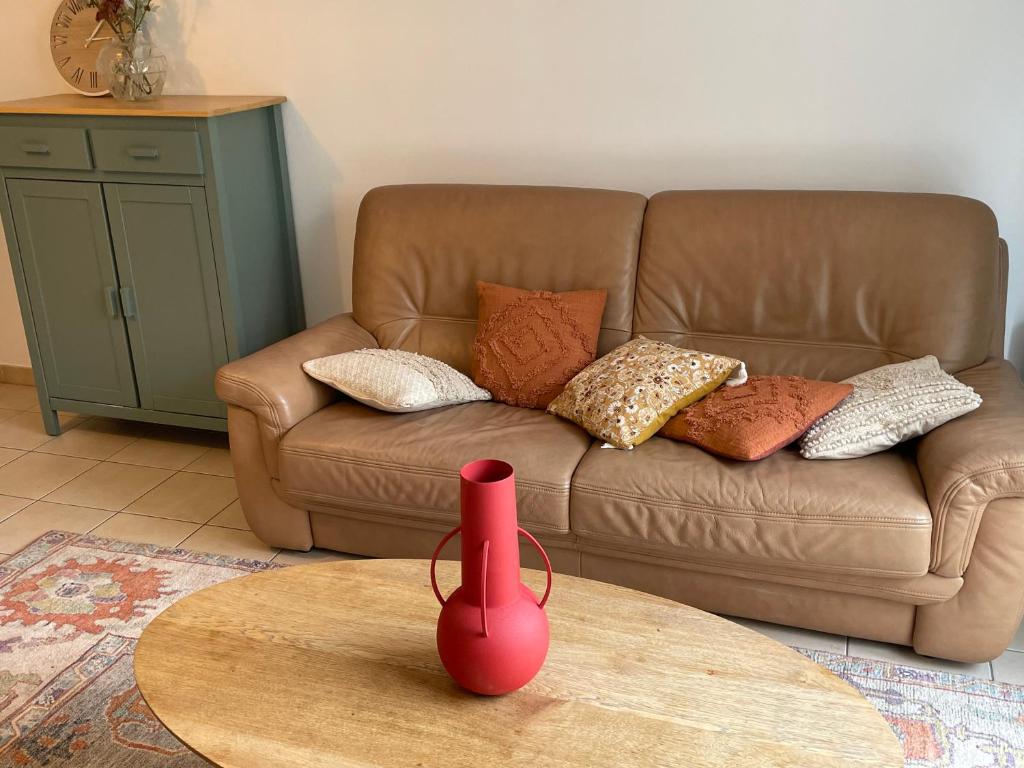 a red vase on a table in front of a couch at Maison agréable et spacieuse aux portes de Paris et du métro in Saint-Ouen