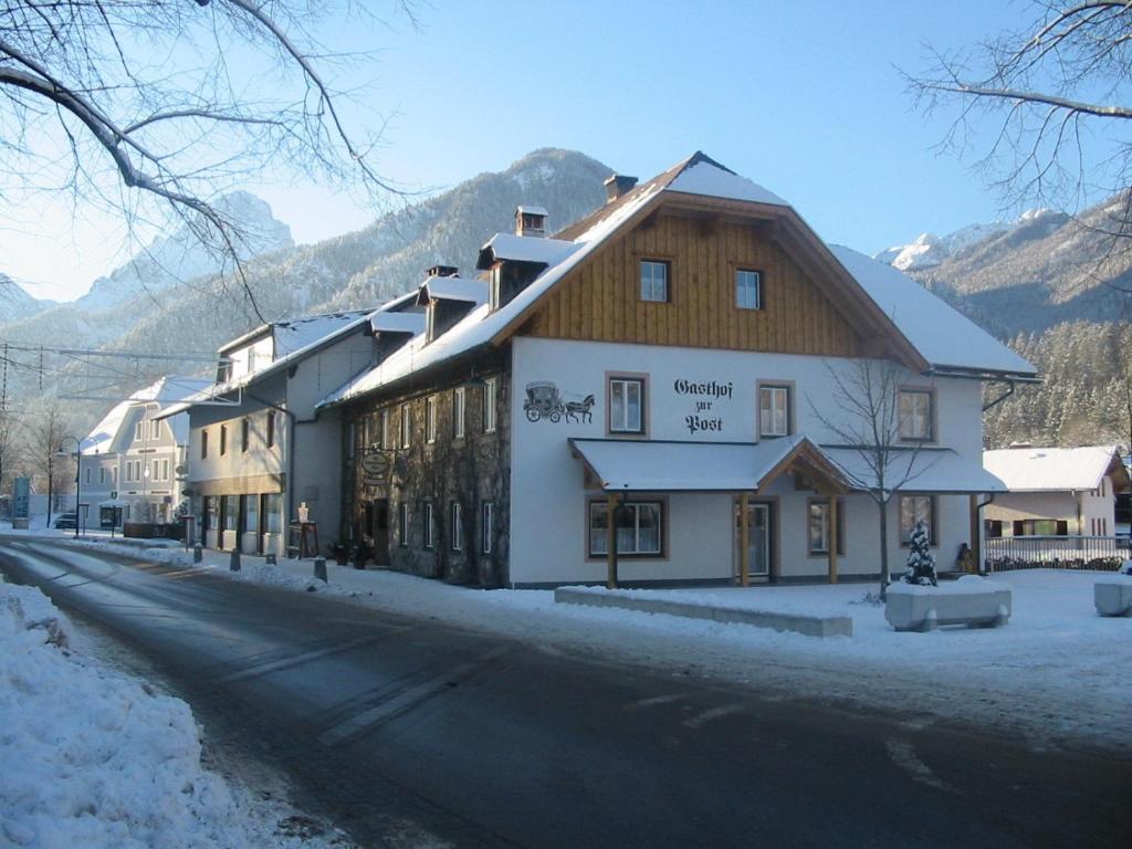 a building on the side of a street with snow at Gasthof zur Post in Hinterstoder