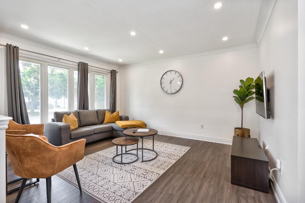 a living room with a couch and a clock on the wall at Bungalow-3 Car Parking-PingPong-BigDeck-BBQ-Close to 403-Appleby Go in Burlington