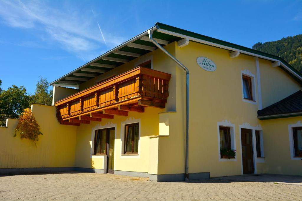 a yellow building with a wooden balcony on it at Pension Milan in Zell am See