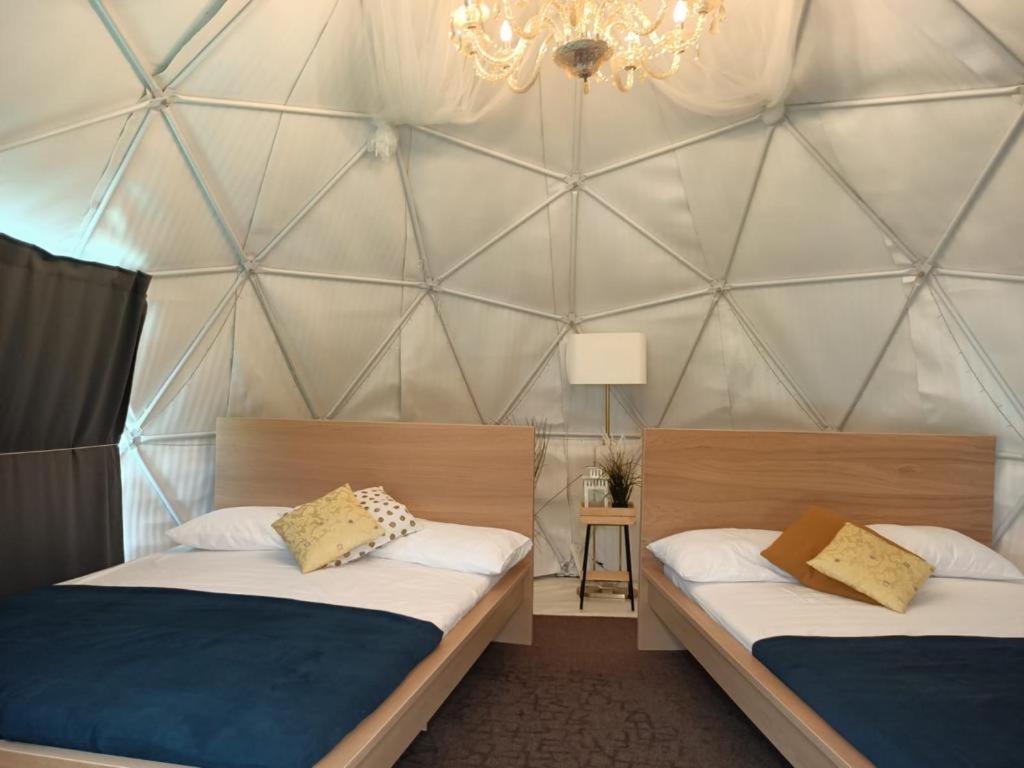 two beds in a room with a triangular wall at Seaside Glamping@Heritage Chalet in Singapore