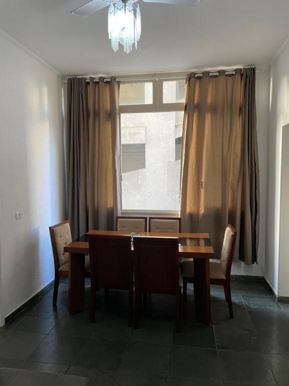 a dining room with a table and chairs and a window at Apartamento na praia com estacionamento Pé na areia Guarujá in Guarujá